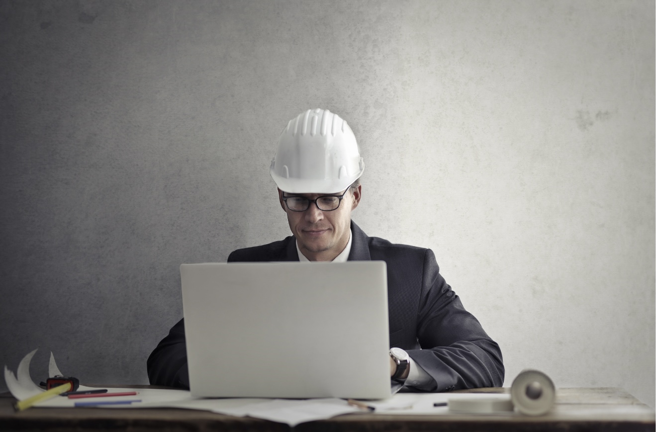  Man in suit and hard hat working on a laptop