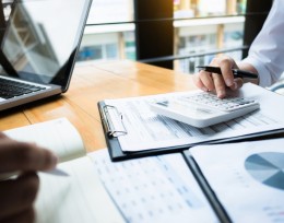 Image of a man sitting at a desk using a calculator 