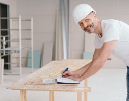 Image of a man in a hard hat standing at a table at a work site 
