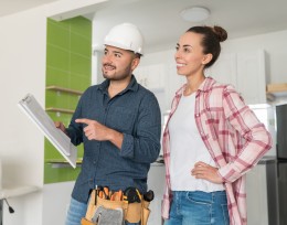 Image of a builder at site with his female client looking at plans