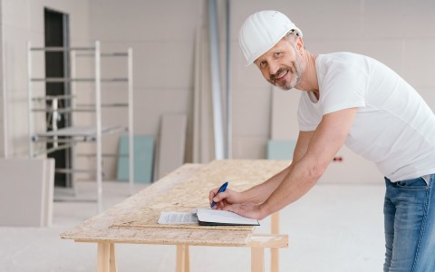 Image of a man in a hard hat standing at a table at a work site 